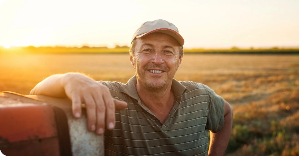 Man in field leaning on equipment