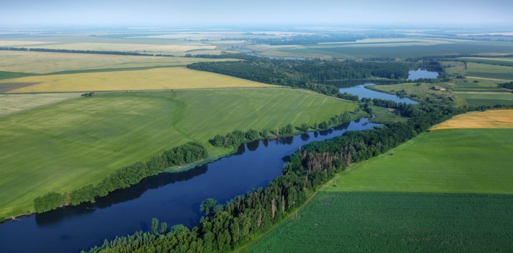 Aerial View Above The Green Fields And River